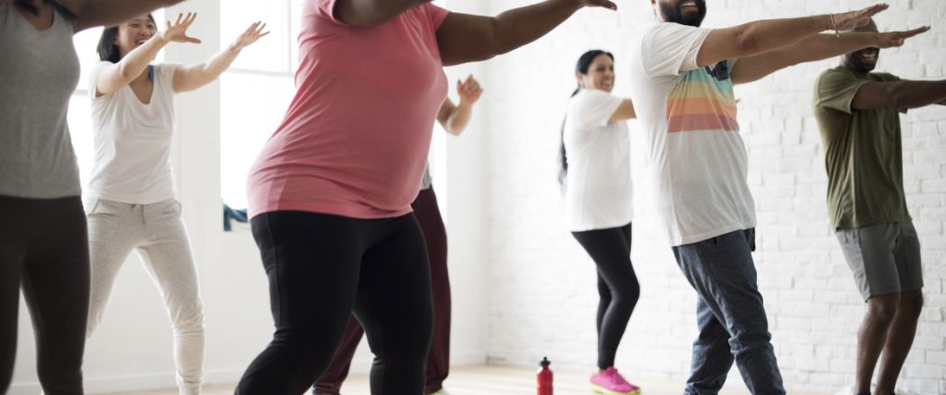 people engaging in an exercise class with their arms reached out in front of them