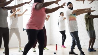 people engaging in an exercise class with their arms reached out in front of them