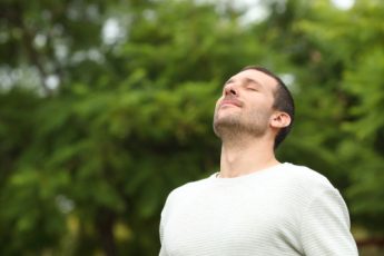 male with eyes closed and relaxed facial expressions whilst outside