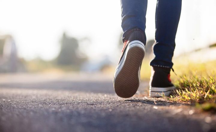 close up of a person's lower legs and shoes as they are walking along a path